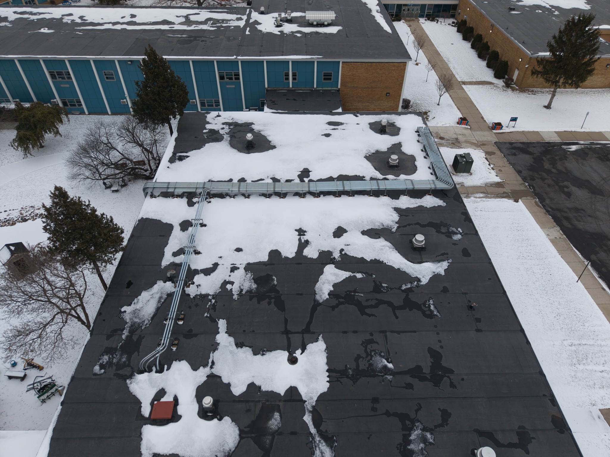 Overhead documentation of a snow-covered commercial roof and conduit